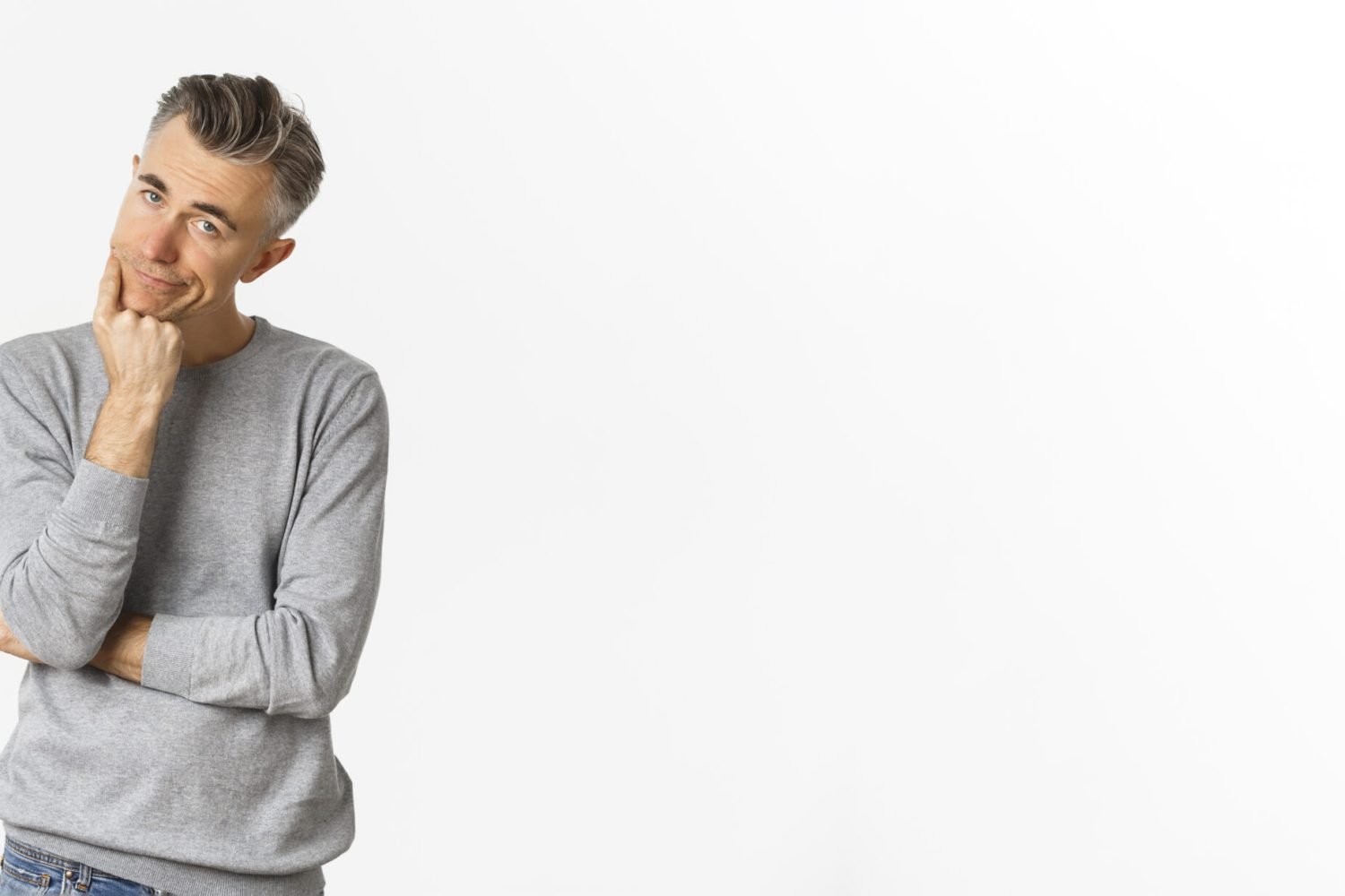 Portrait of bored and unamused middle-aged man in grey sweater, leaning on hand and looking at camera reluctant, standing sad over white background.